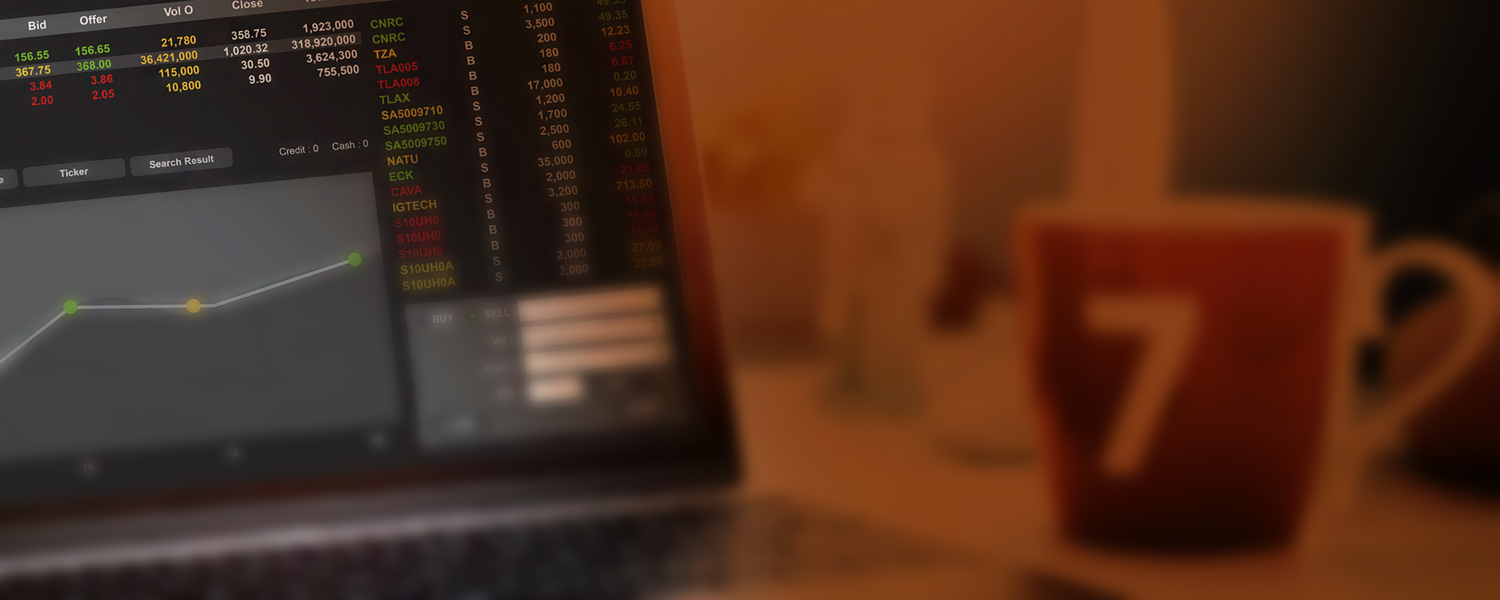 Laptop showing a stock trading terminal with bid, offer and price columns beside a mug marked with the number 7