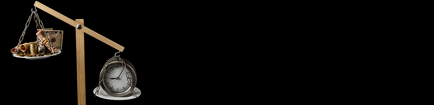 A tilted wooden balance scale weighing a pan of coins and rolled banknotes against an alarm clock on a black background