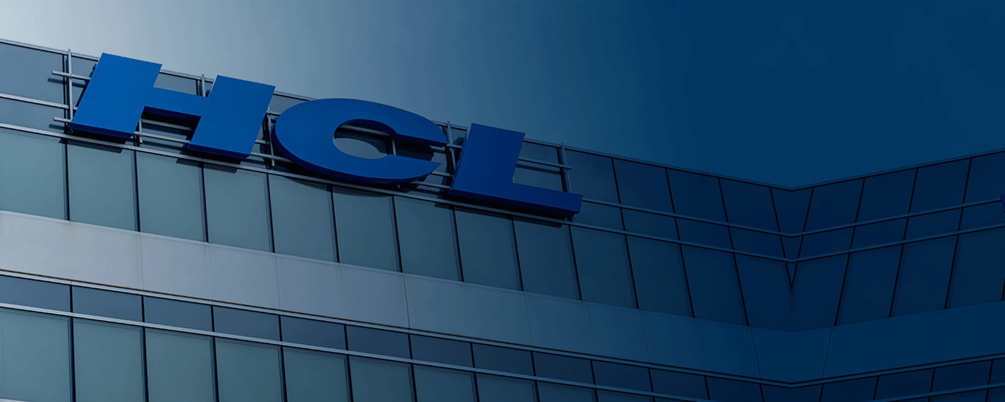 The blue HCL logo mounted on the glass facade at the top of a modern corporate office building