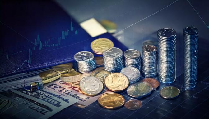 Stacks and scattered coins with banknotes resting on a printed financial chart